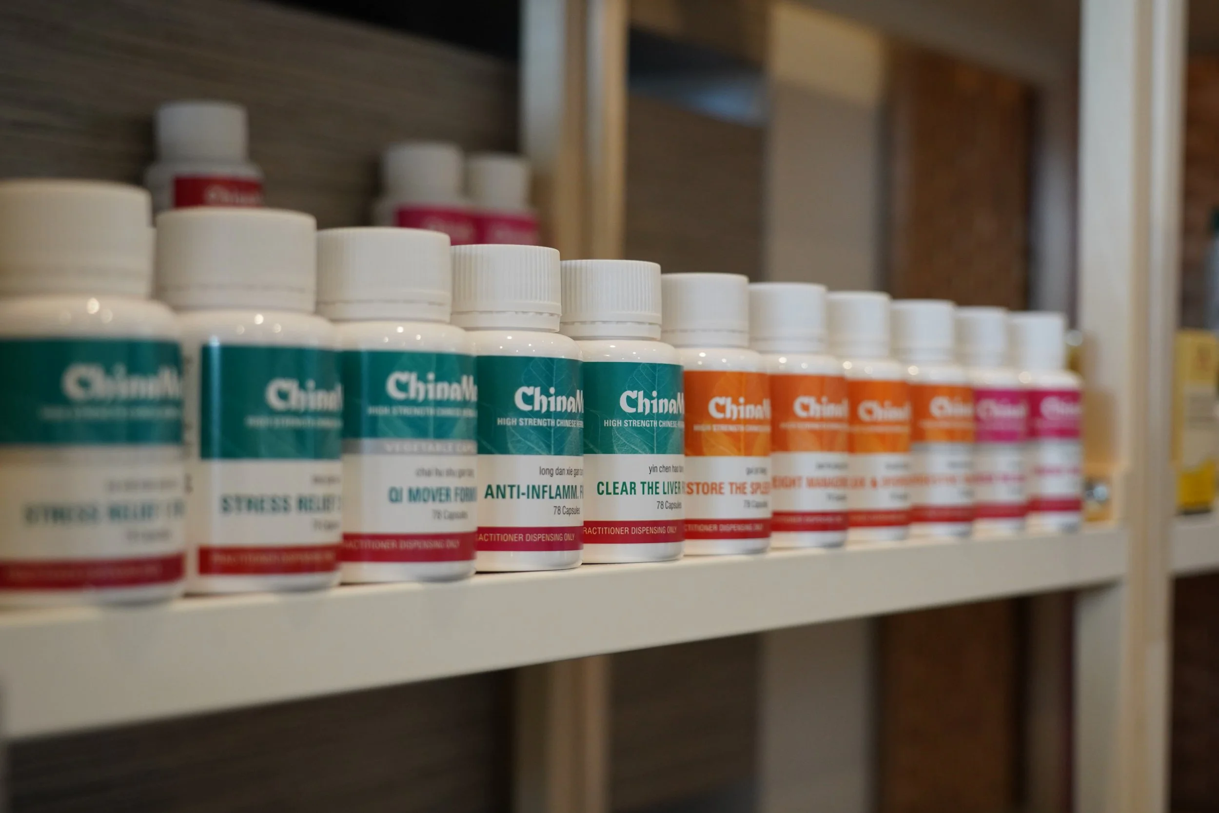 Shelf with bottles of herbal supplements in green, orange, and pink labels.