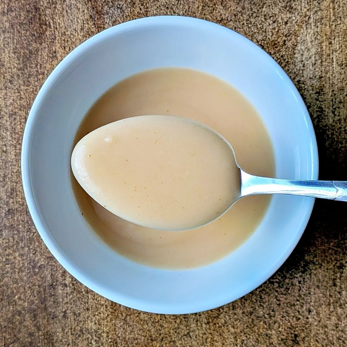 Smooth homemade velouté sauce in a bowl with a spoon showing its velvety consistency