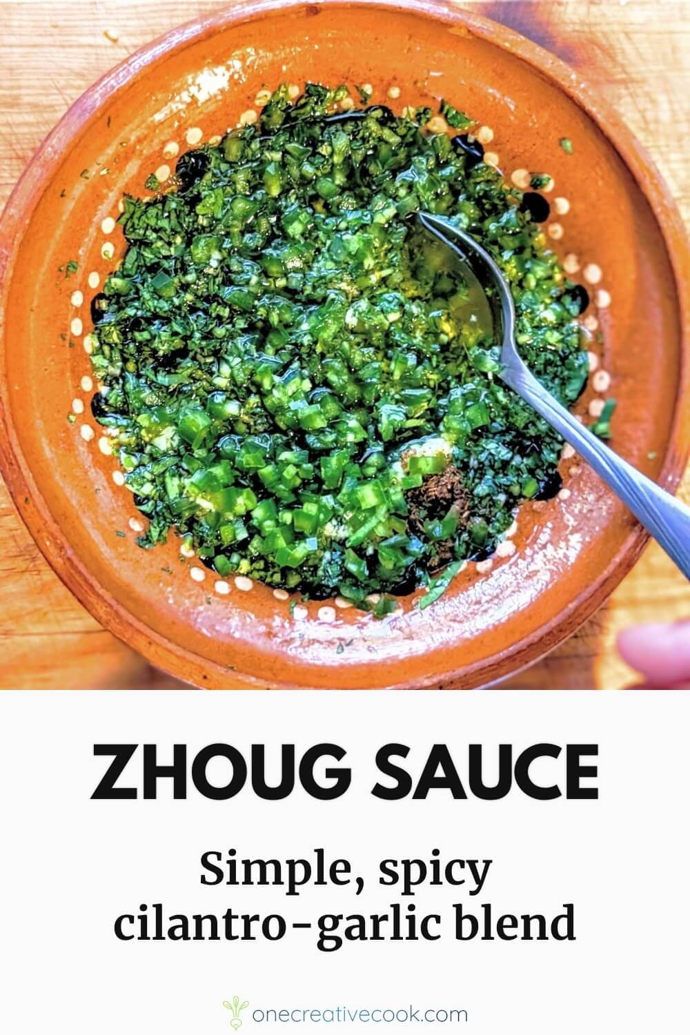 Zhoug sauce in a rustic clay bowl with a spoon, served beside a platter of grilled lamb and colorful summer vegetables