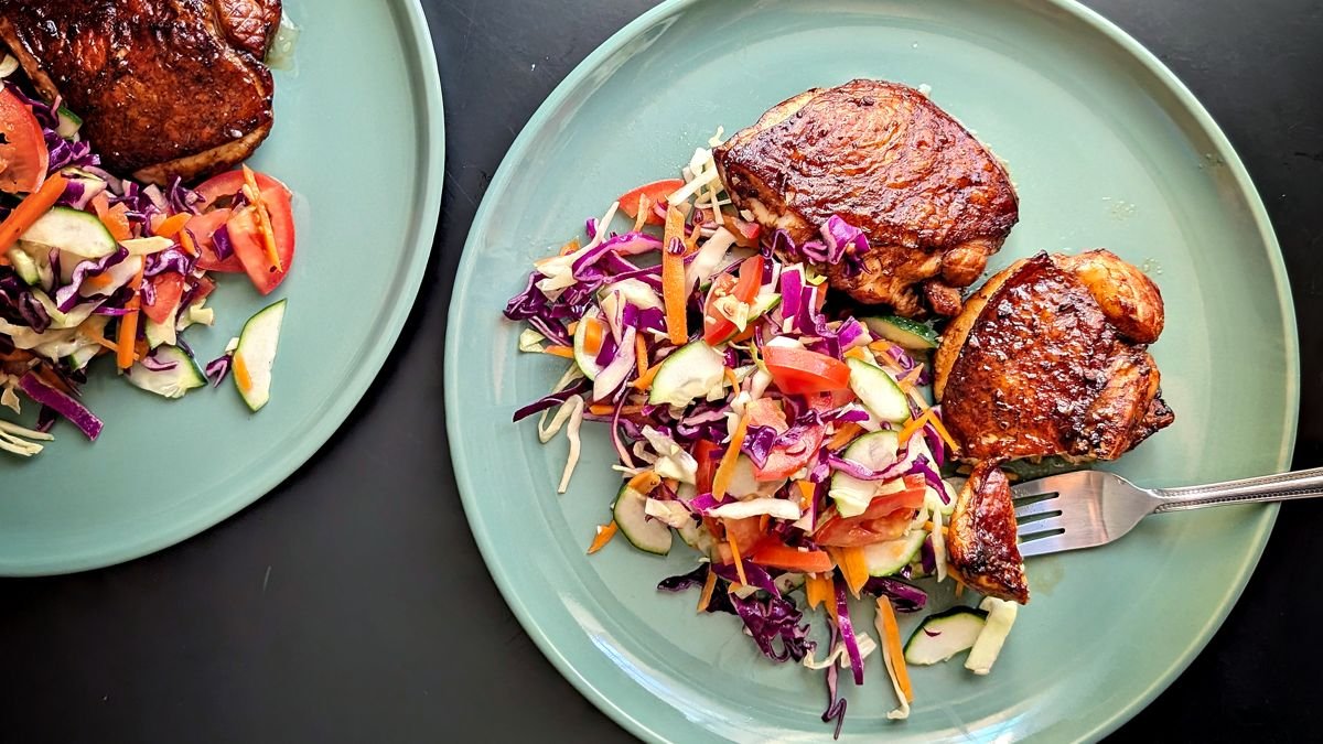 Air fryer balsamic chicken thighs served with fresh cabbage slaw on a two plates