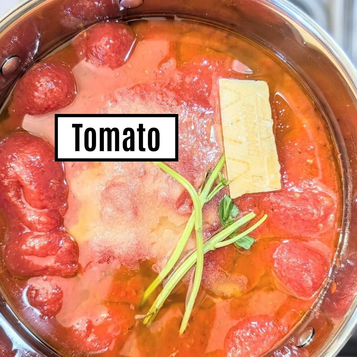 Italian style tomato mother sauce with a cheese rind and basil stems showing