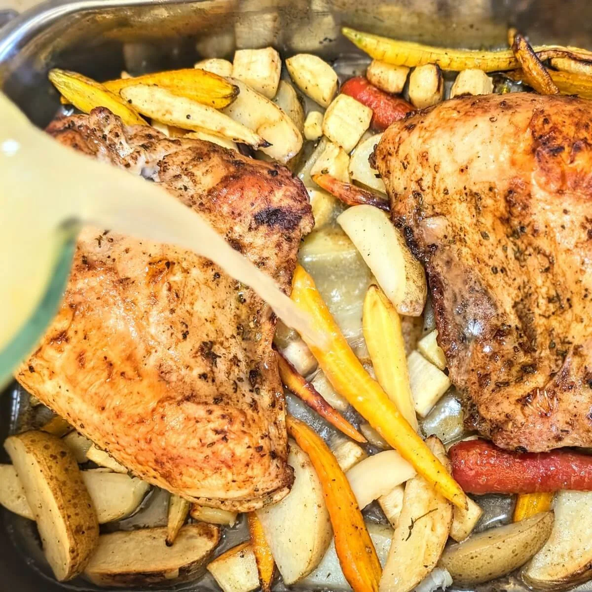 Pouring chicken stock into the pan to finish cooking the dry brine turkey breasts