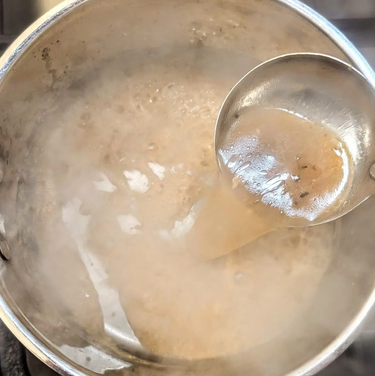 Pouring turkey pan drippings into a saucepan to make homemade gravy