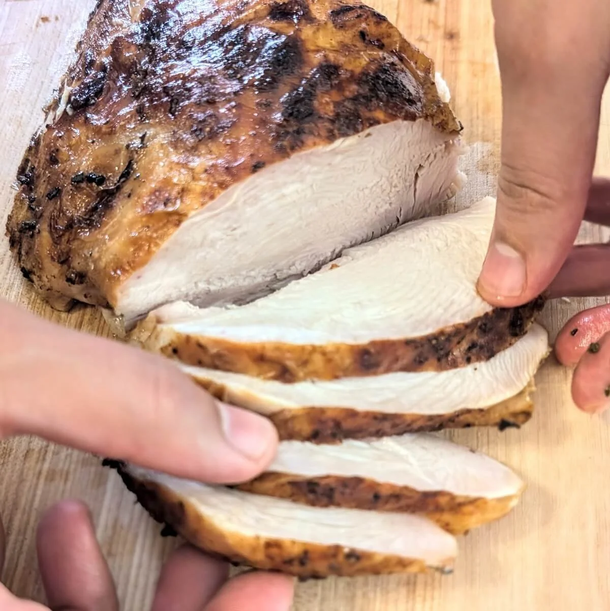 Close-up of juicy sliced turkey breast being fanned out on a wooden cutting board