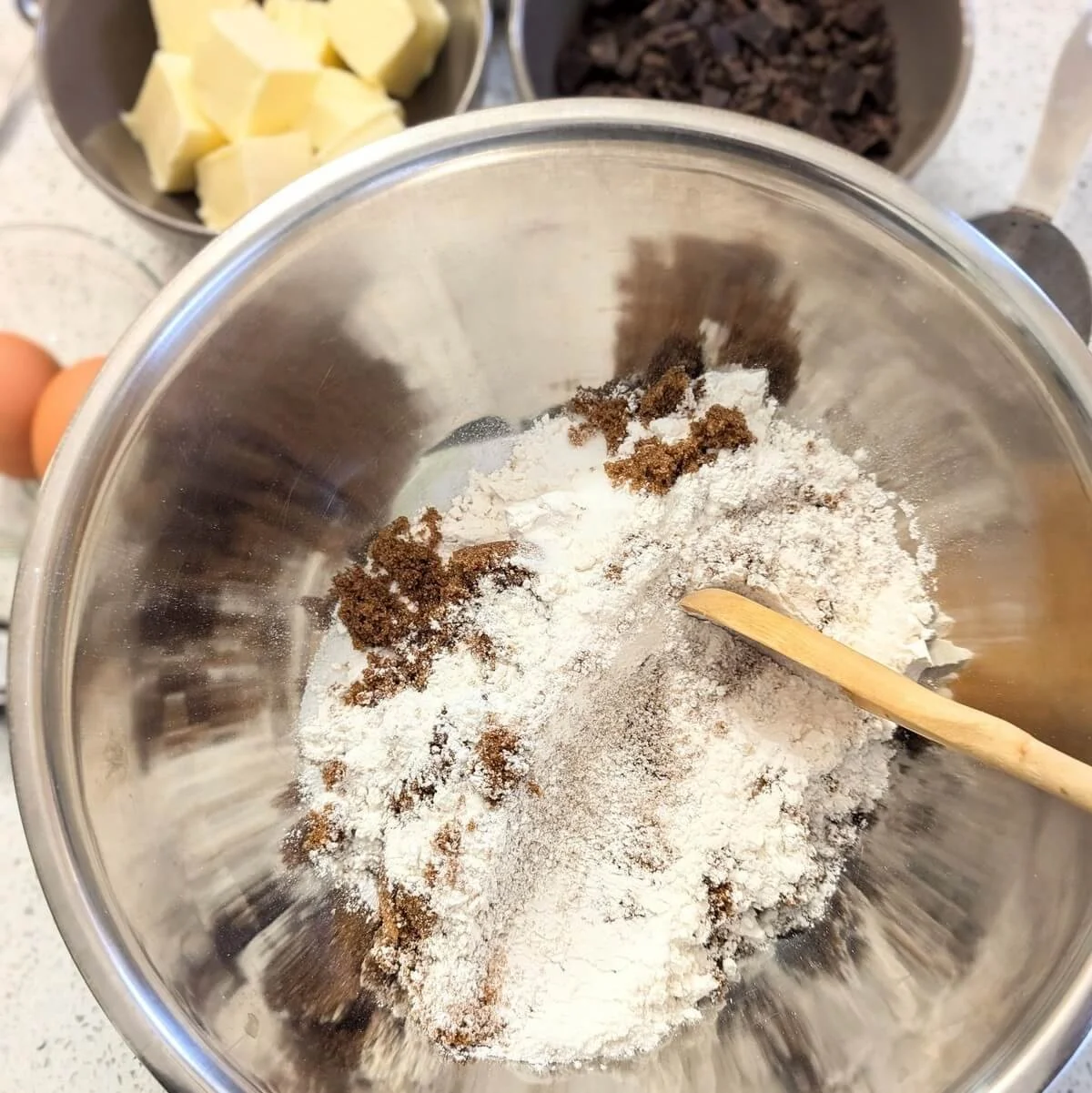 Mixing flour, sugars, and baking soda for salted dark chocolate cookies in a bowl