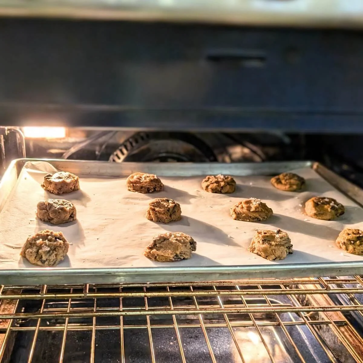 Sea salt dark chocolate cookies baking in the oven on a parchment-lined sheet
