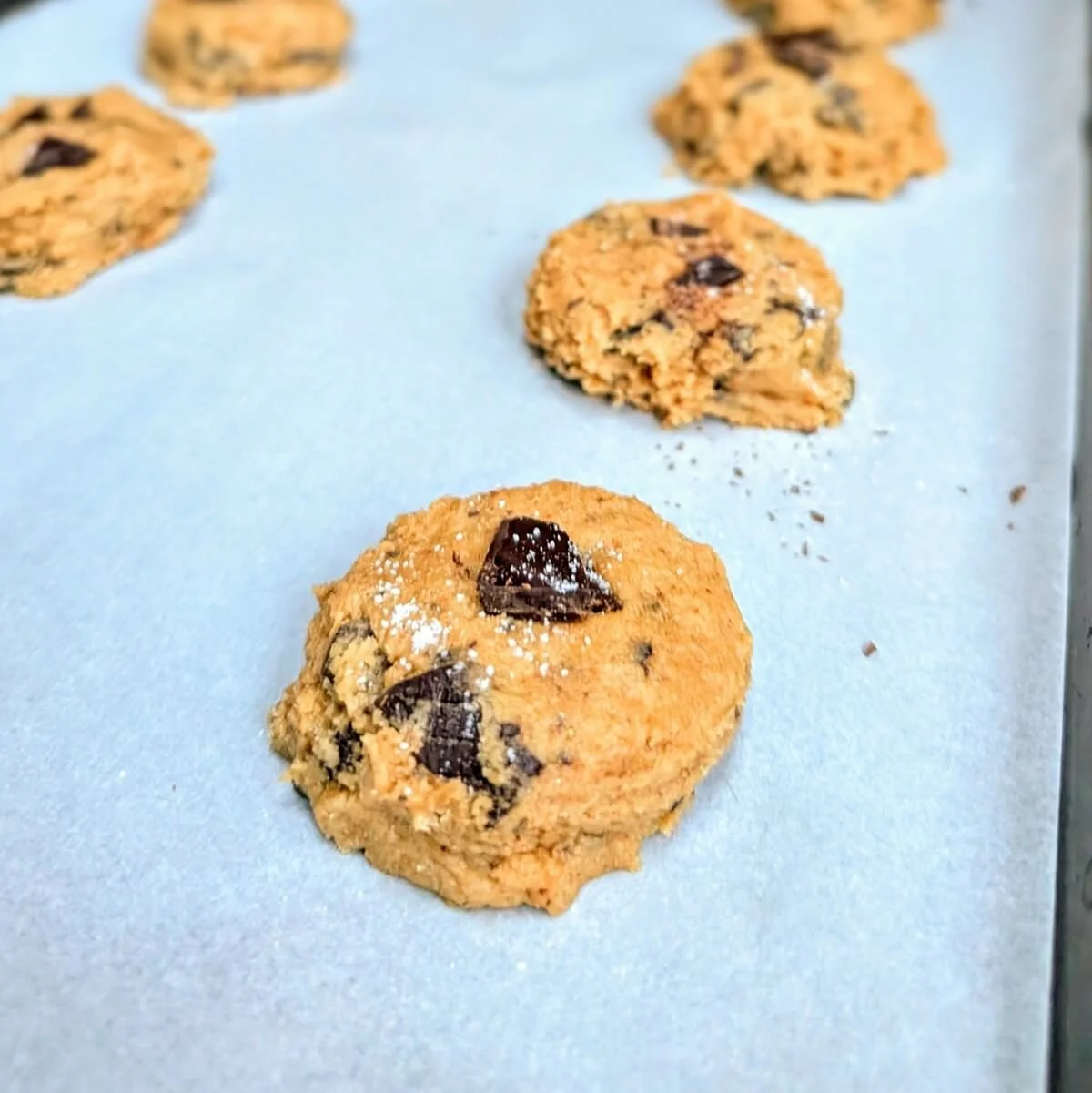 Side angle of chocolate sea salt cookie dough balls arranged on a baking tray