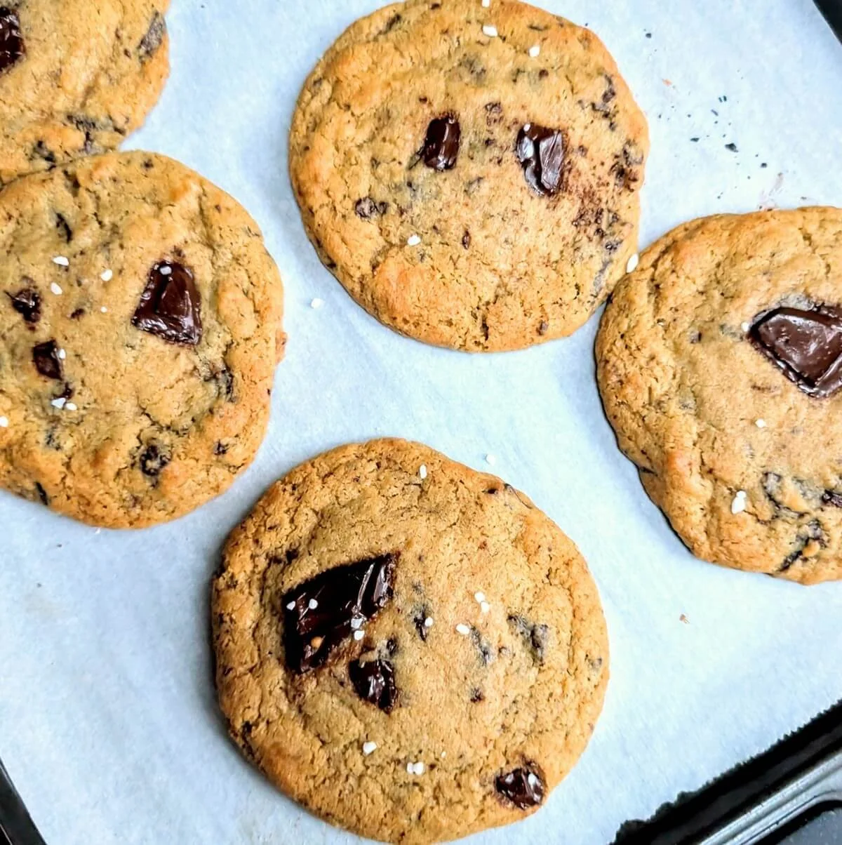 Freshly baked salted dark chocolate cookies cooling on a baking tray