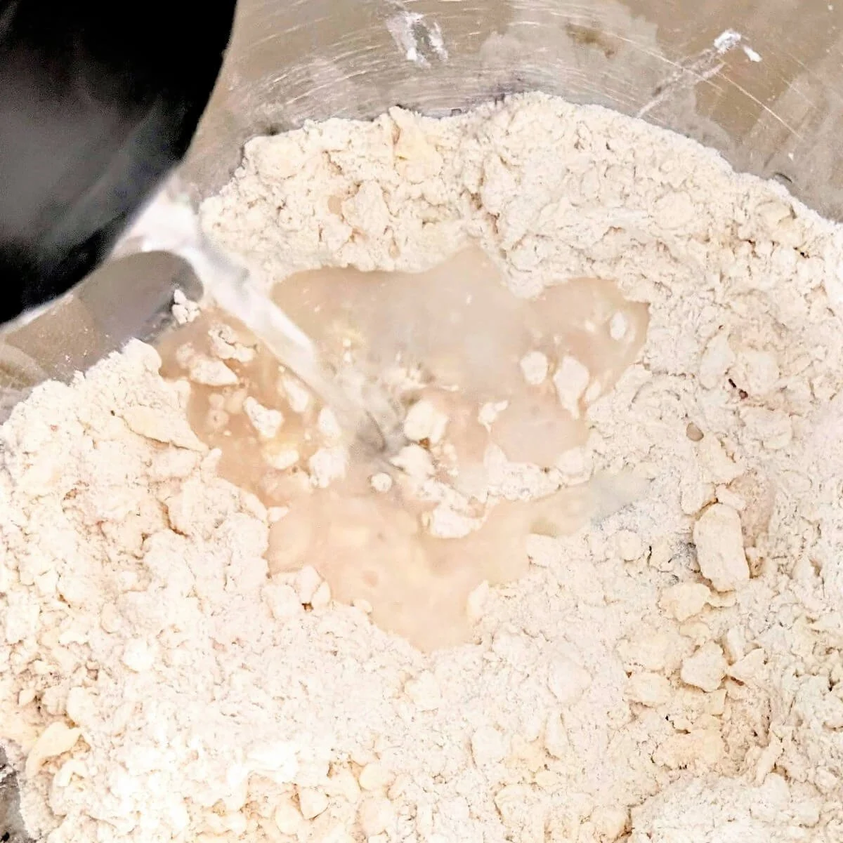 Water is being added to the flour and butter mixture to make pie crust from scratch