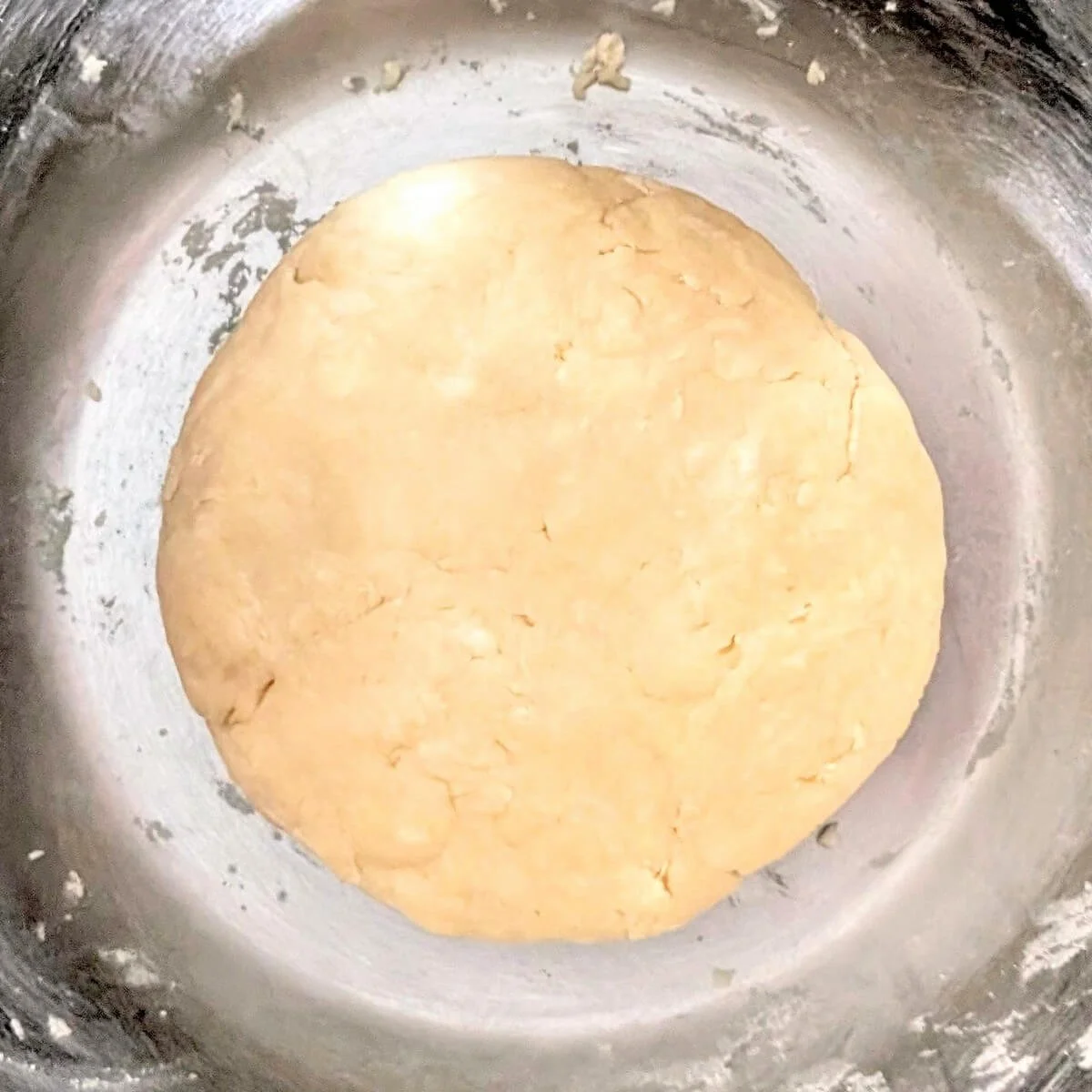 Homemade pie dough shaped into a disc in a bowl
