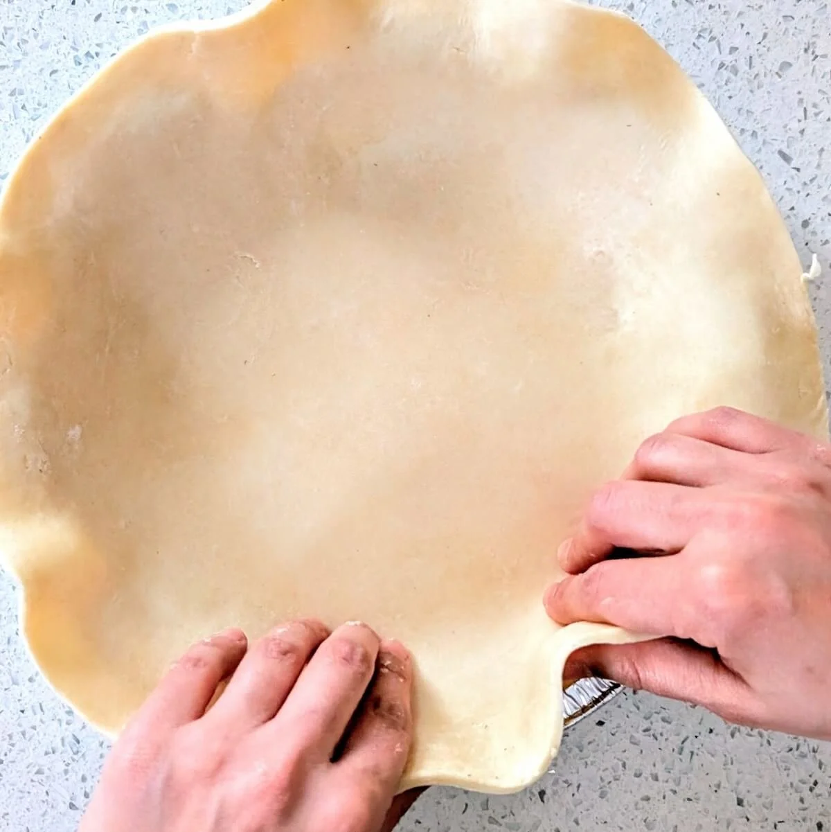 Homemade pumpkin pie crust being pressed into a pie pan