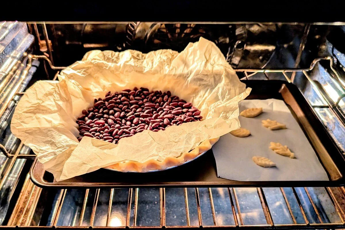 Blind baking a pie crust with kidney bean weights to make pumpkin pie