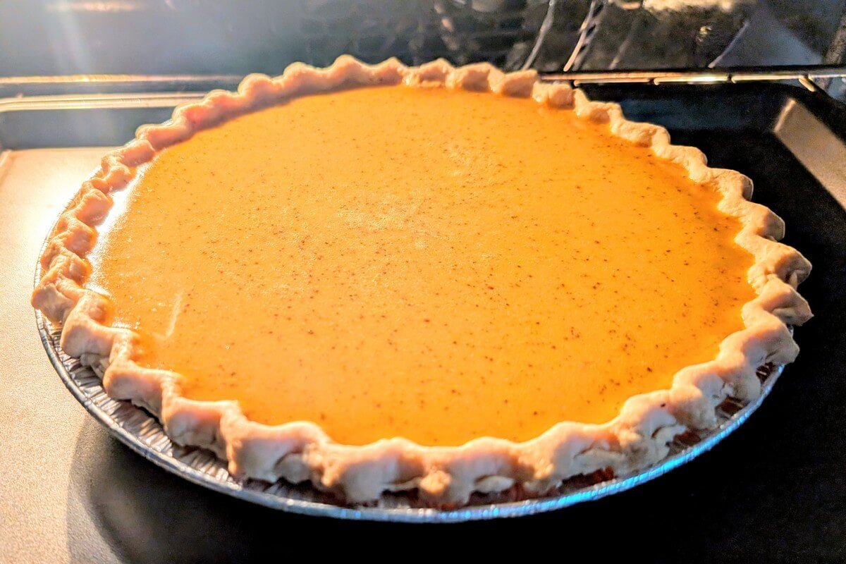Pumpkin pie crust filled with smooth homemade pumpkin filling in the oven