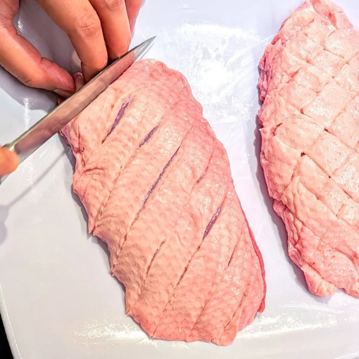 Scoring duck breast skin with a sharp knife to prepare crispy duck breast