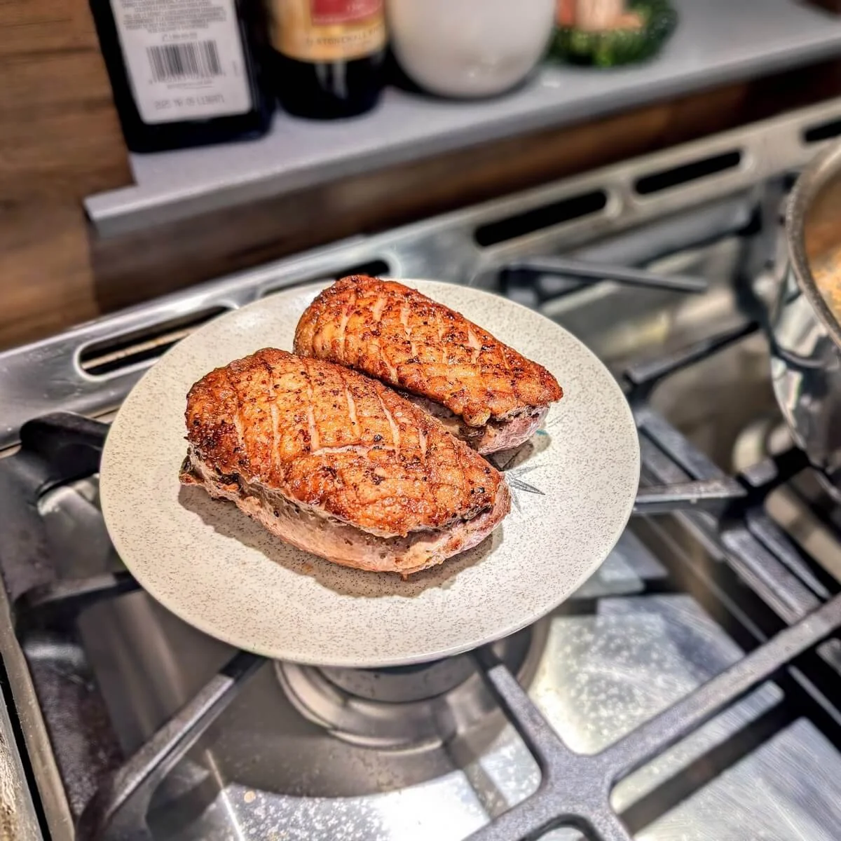Resting crispy duck breasts uncovered on a plate after cooking