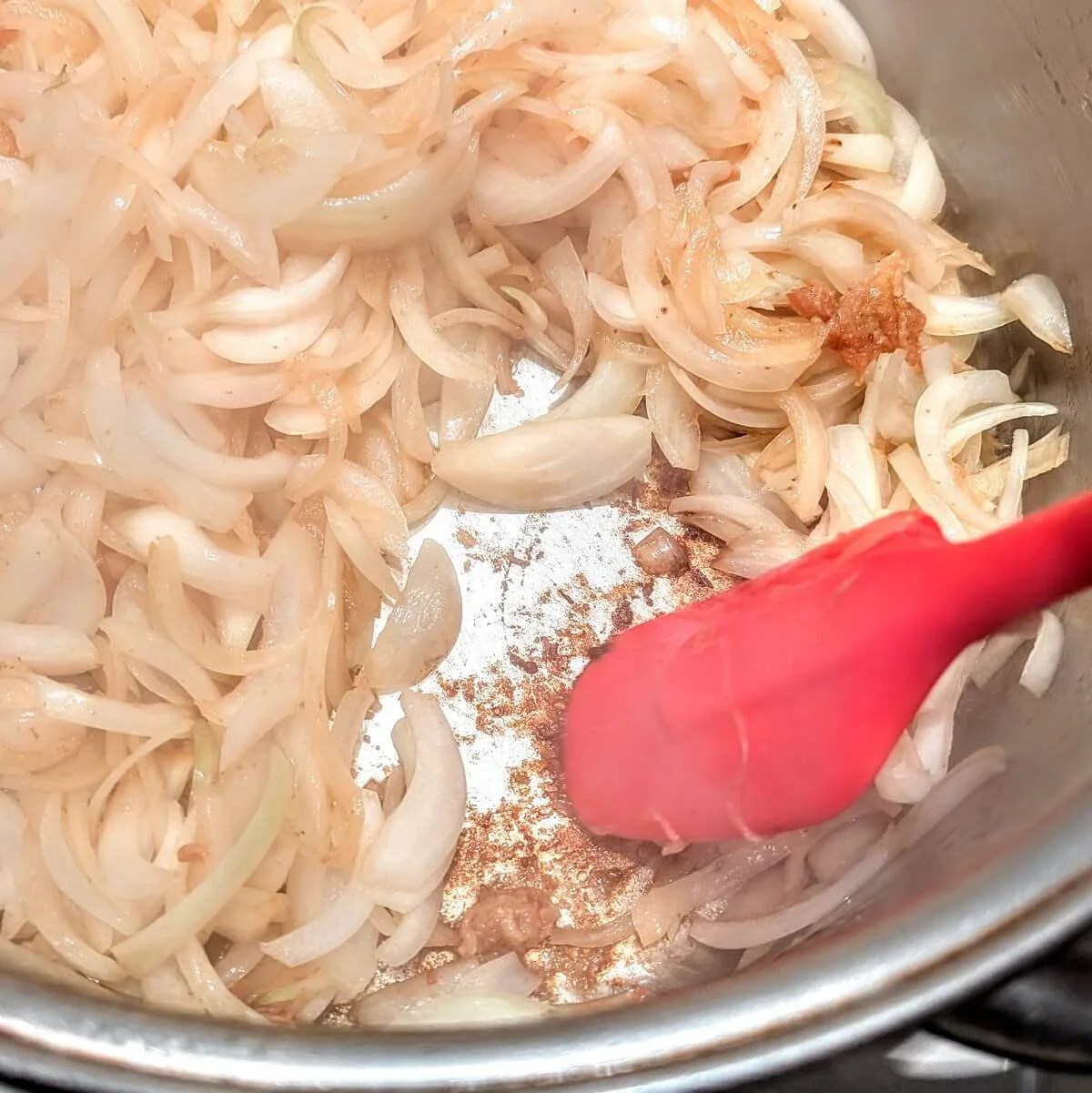 Softened onions stirred with a spatula to build the base for traditional Moroccan chicken tagine