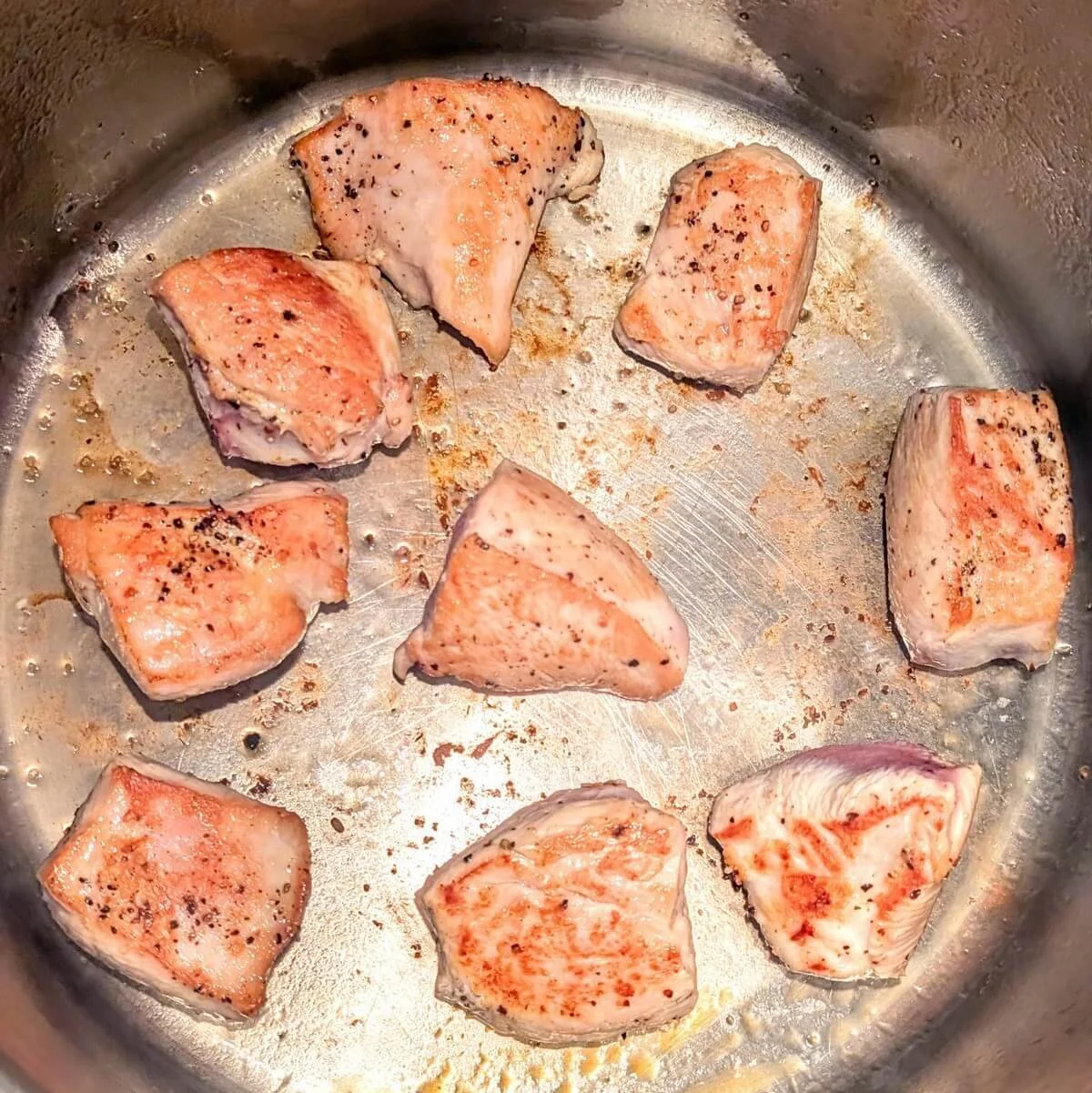 Golden-browned turkey breast searing in a heavy-bottomed pot for turkey cacciatore