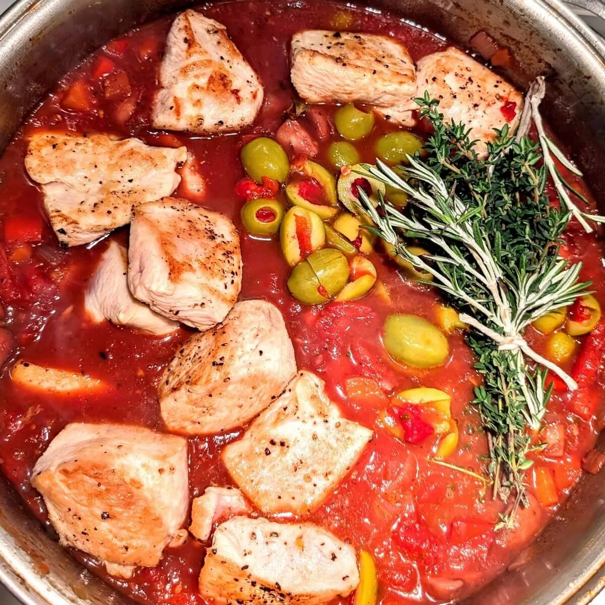Turkey breast, green olives, and fresh herbs added to the pot for cacciatore stew