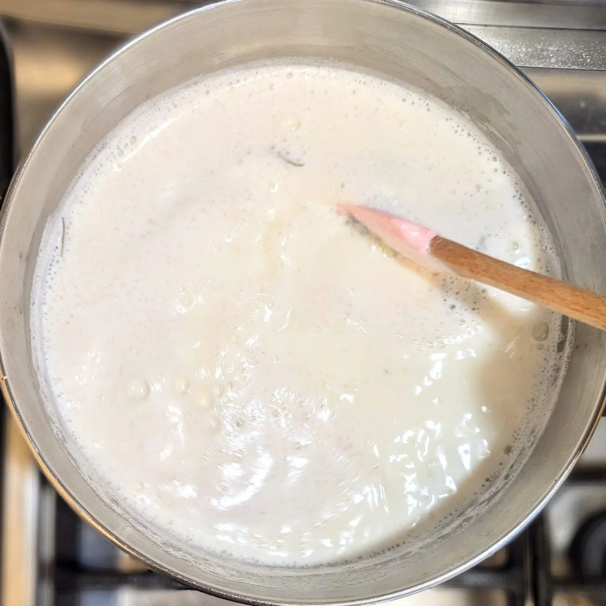 Milk mixture for bechamel sauce foaming gently as it’s stirred with a spatula