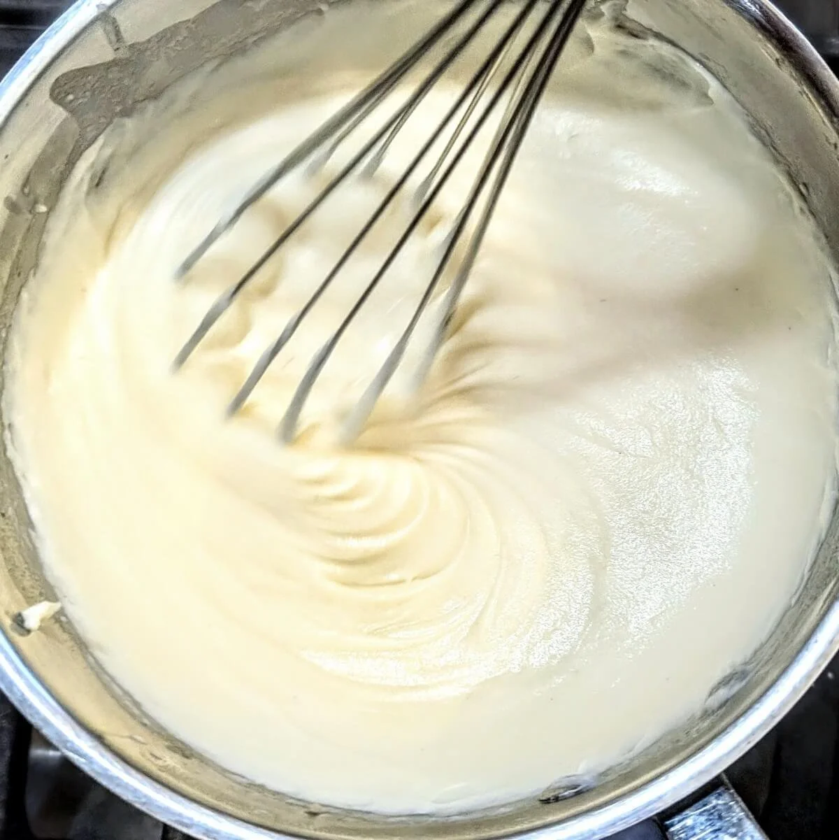 Bechamel sauce becoming smoother as more milk is whisked in