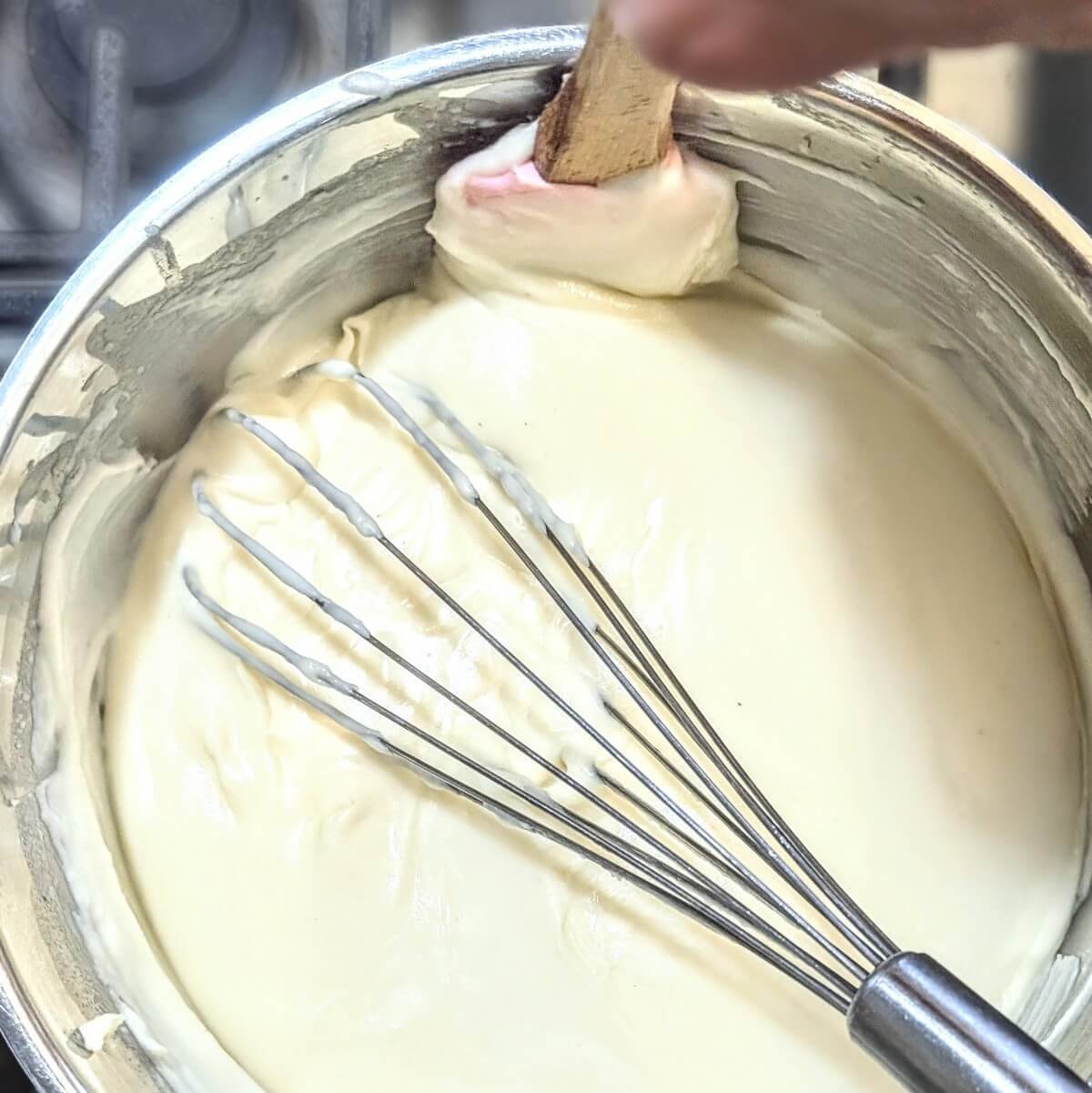 A spatula scraping the edges of the pan to ensure the sauce doesn’t stick