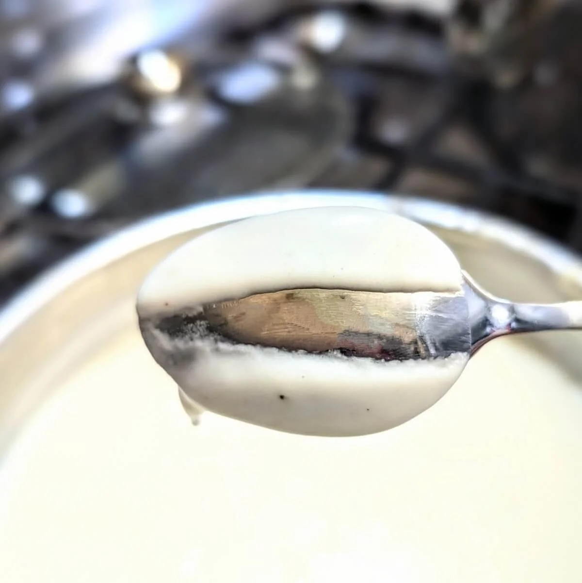 A spoon coated with bechamel sauce, showing the nappe consistency by drawing a line through it to check the thickness