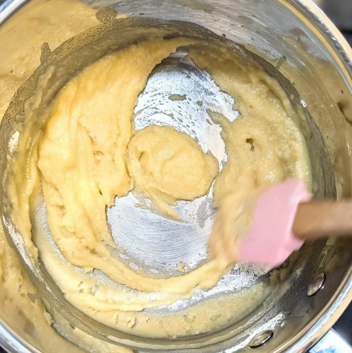 White roux foaming and being stirred in a saucepan as it cooks for bechamel sauce