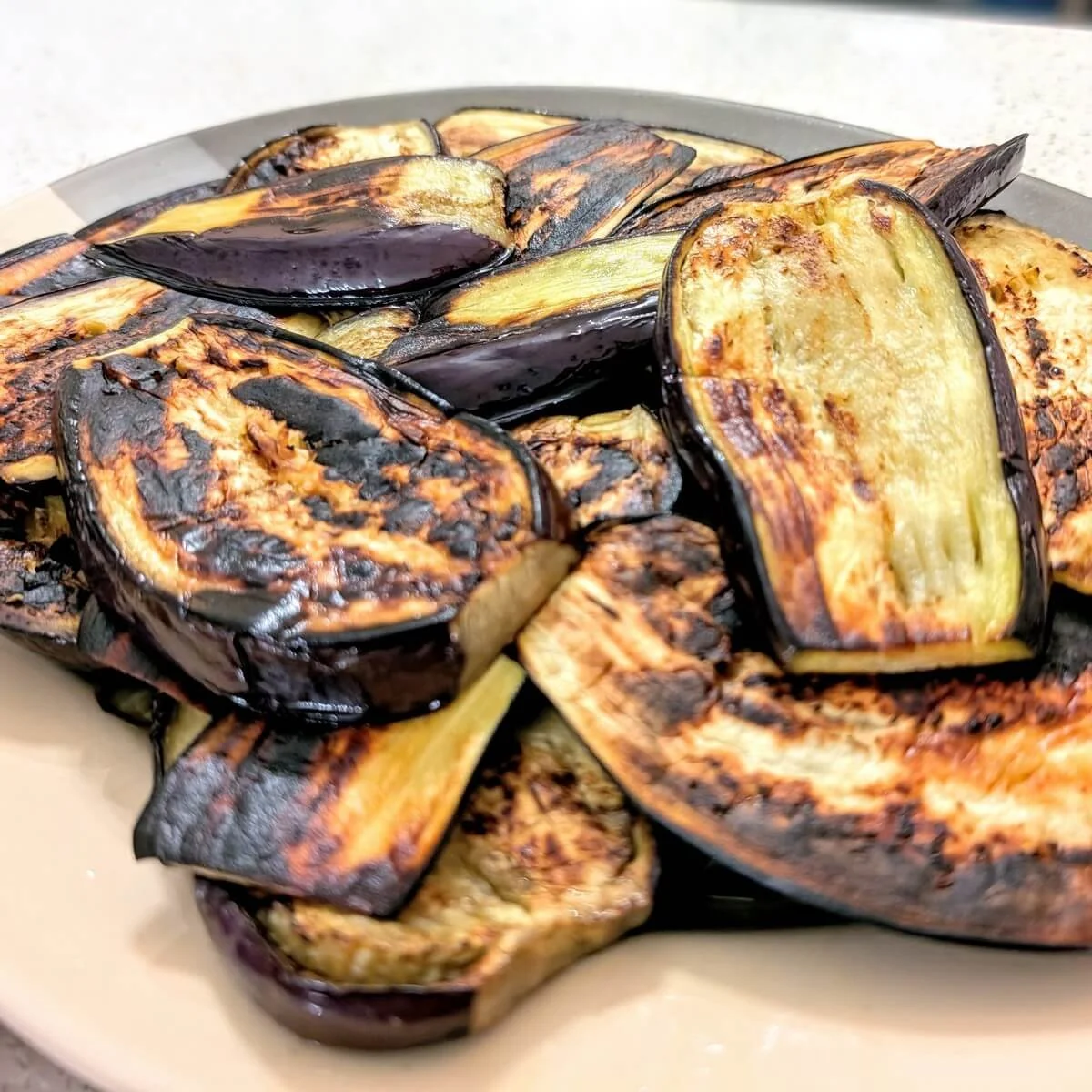 Deeply browned eggplant slices set aside on a platter before assembling the Iraqi eggplant stew