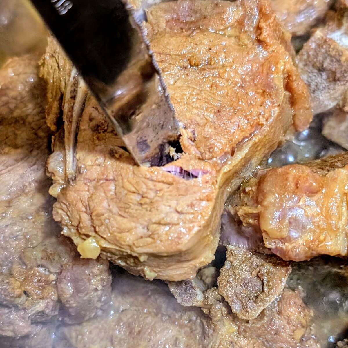 Knife twisting into a lamb t-bone chop to check for tenderness