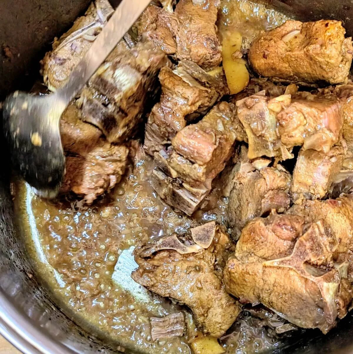 Lamb being stirred as the cooking liquid reduces