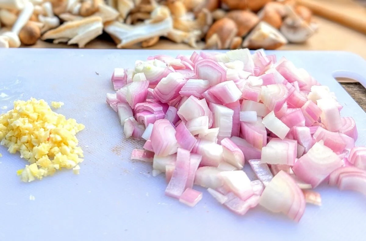 Diced shallots and minced garlic on cutting board for camping risotto