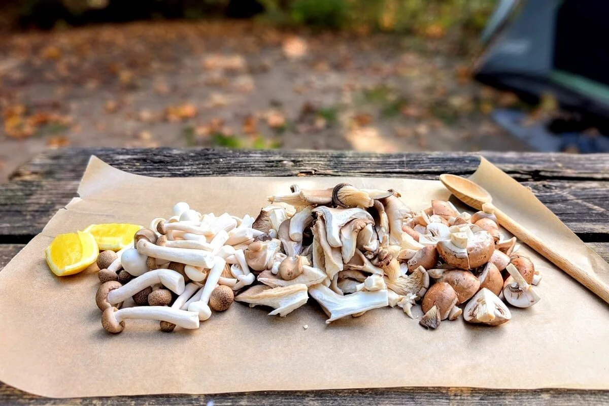 Sliced mixed mushrooms on parchment paper for campfire mushroom risotto