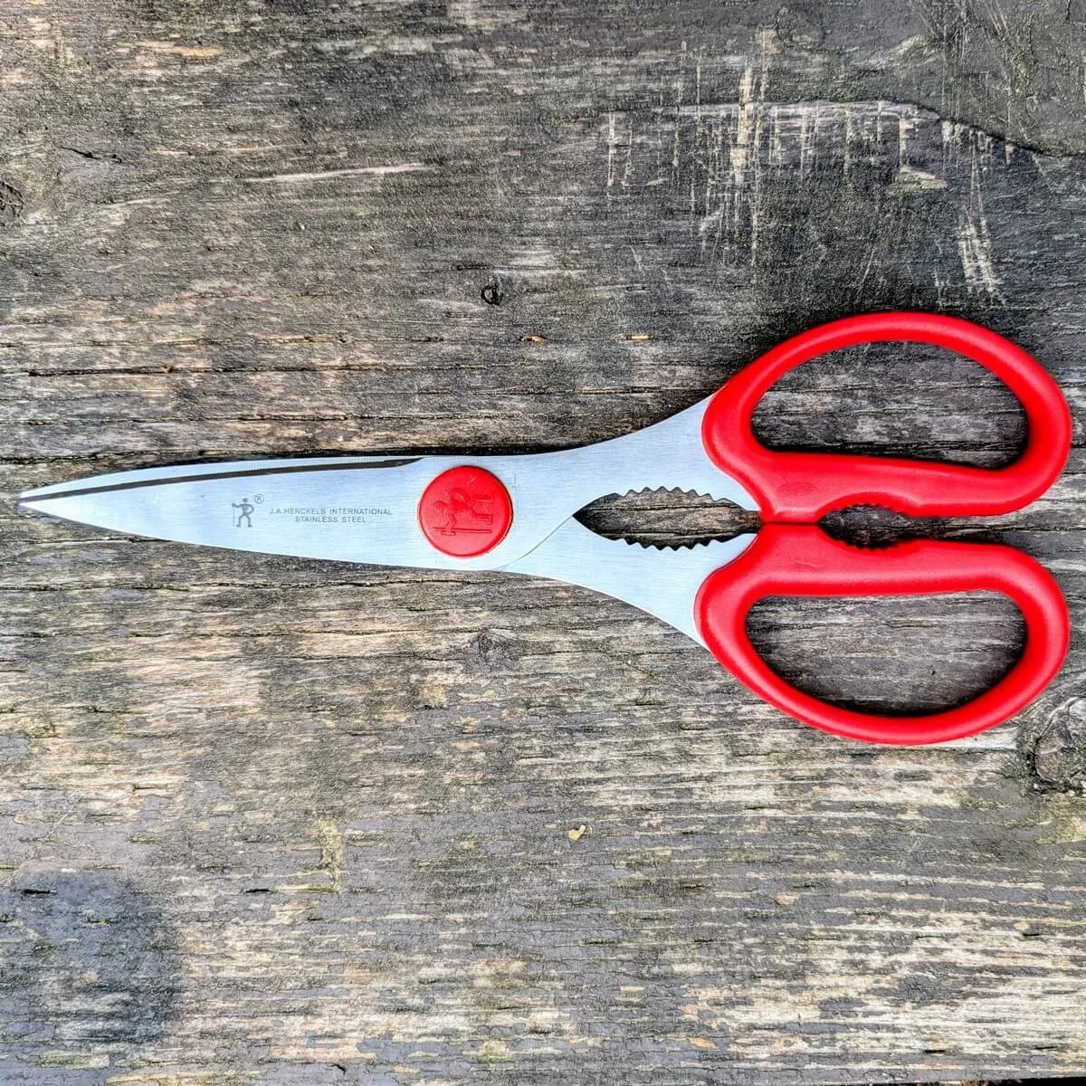 Red handle kitchen scissors on wooden camp table for campfire cooking prep
