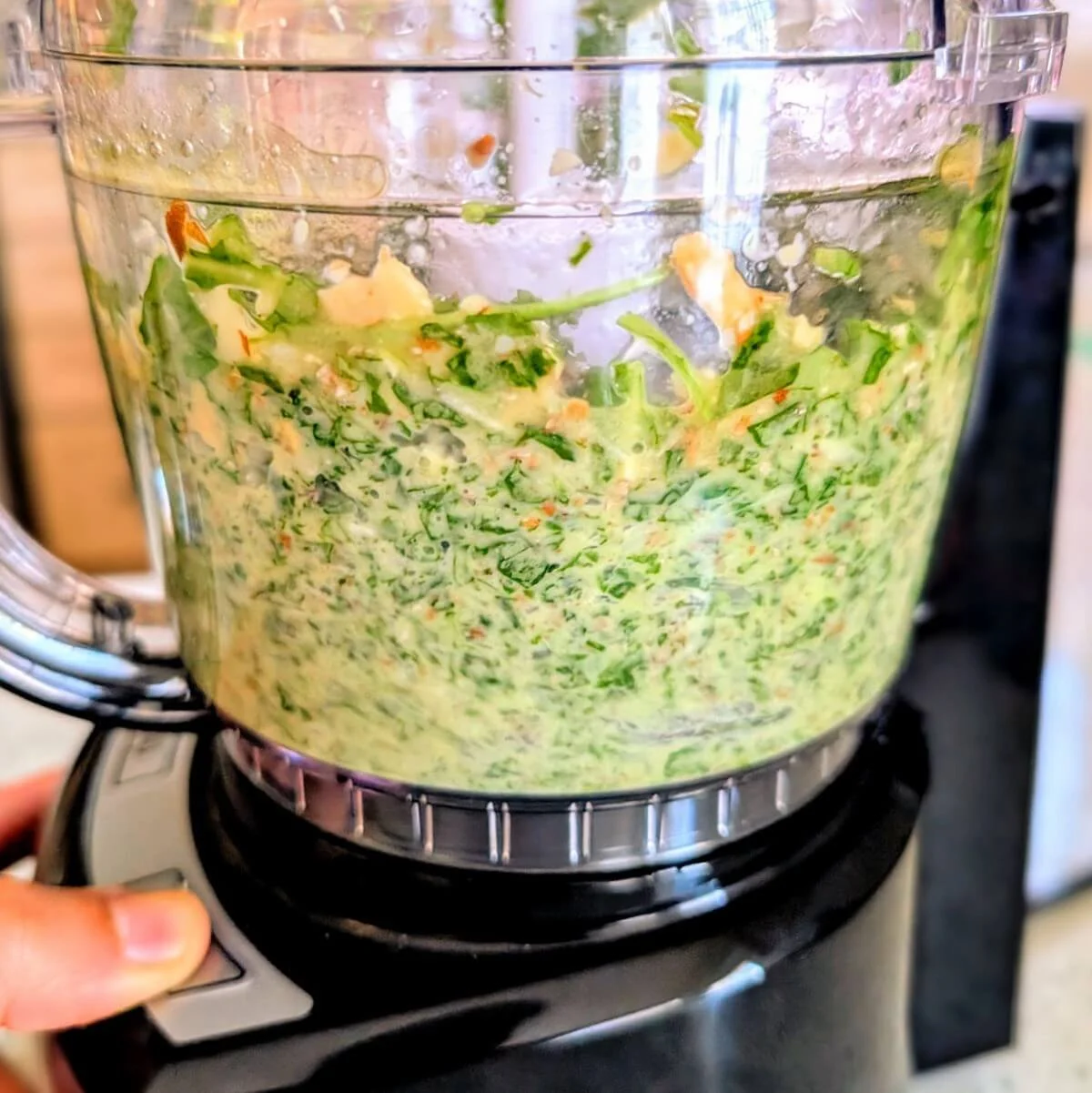Food processor blending arugula basil walnut pesto as the greens break down