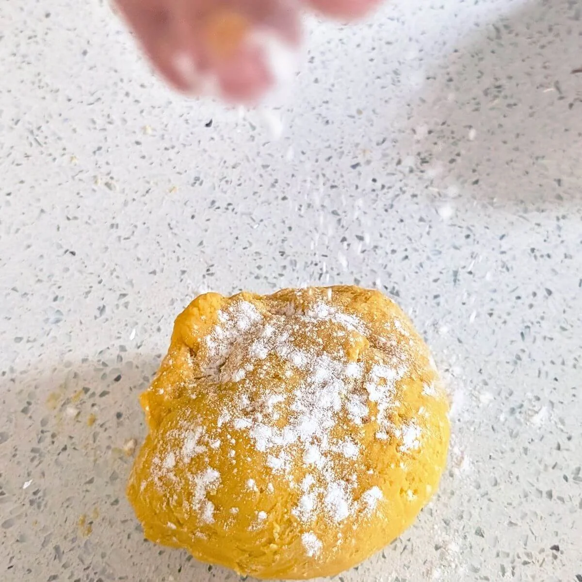 Lightly dusting flour over slightly sticky pasta dough to adjust hydration