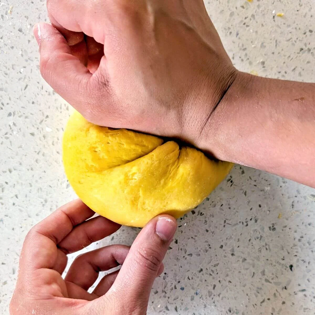 Using the heel of the palm to push and stretch pasta dough across the countertop
