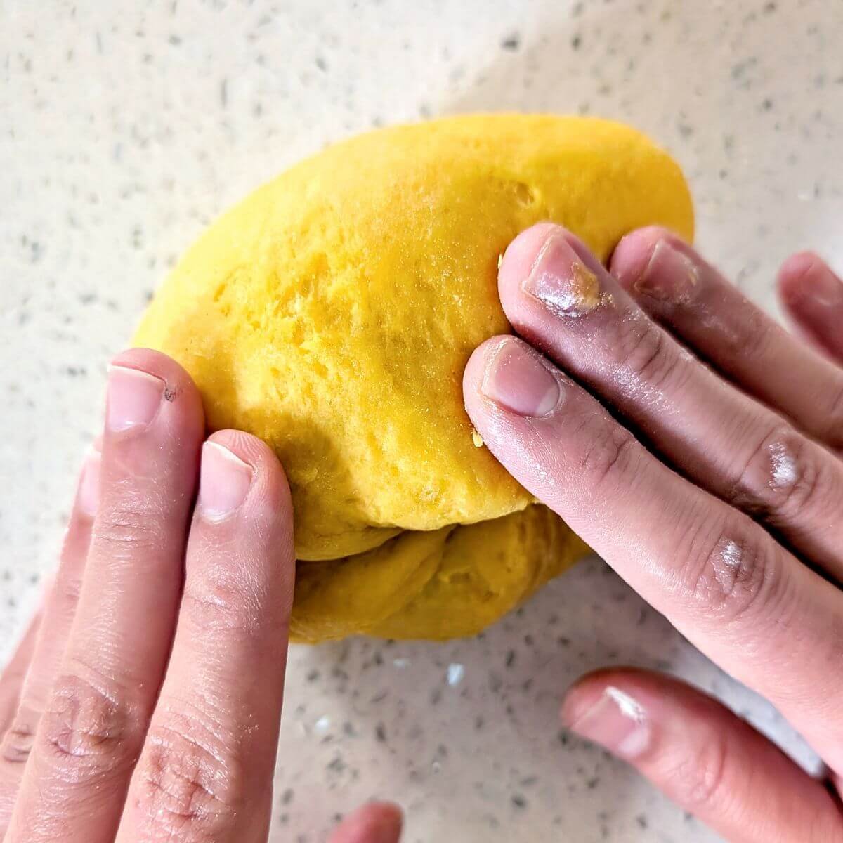 Folding the pasta dough back over itself after each push to build structure