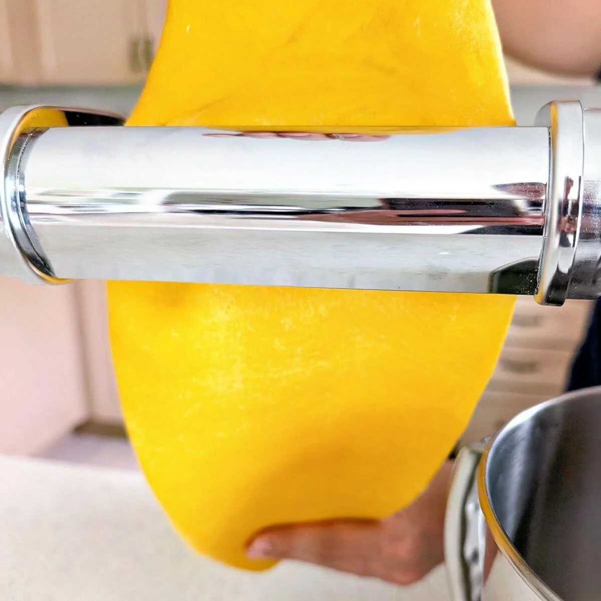 Fresh pasta sheet passing through a pasta machine during lamination