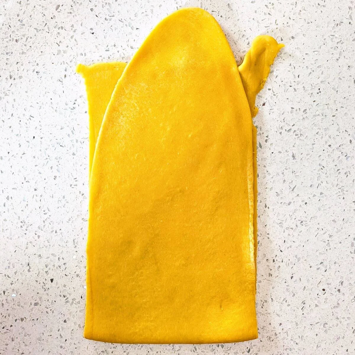 Fresh pasta dough folded in half to laminate before rolling thinner sheets