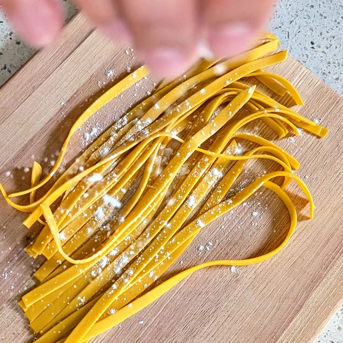 Sprinkling flour over freshly cut pasta to prevent the strands from sticking