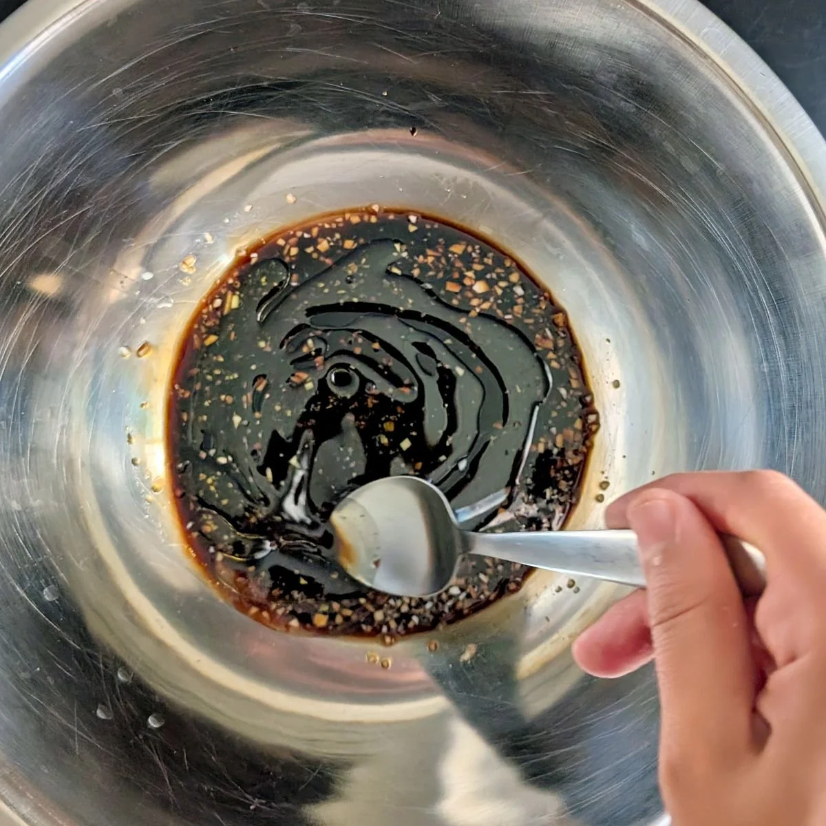 Balsamic vinegar, soy sauce, and olive oil being stirred together for air fryer chicken marinade