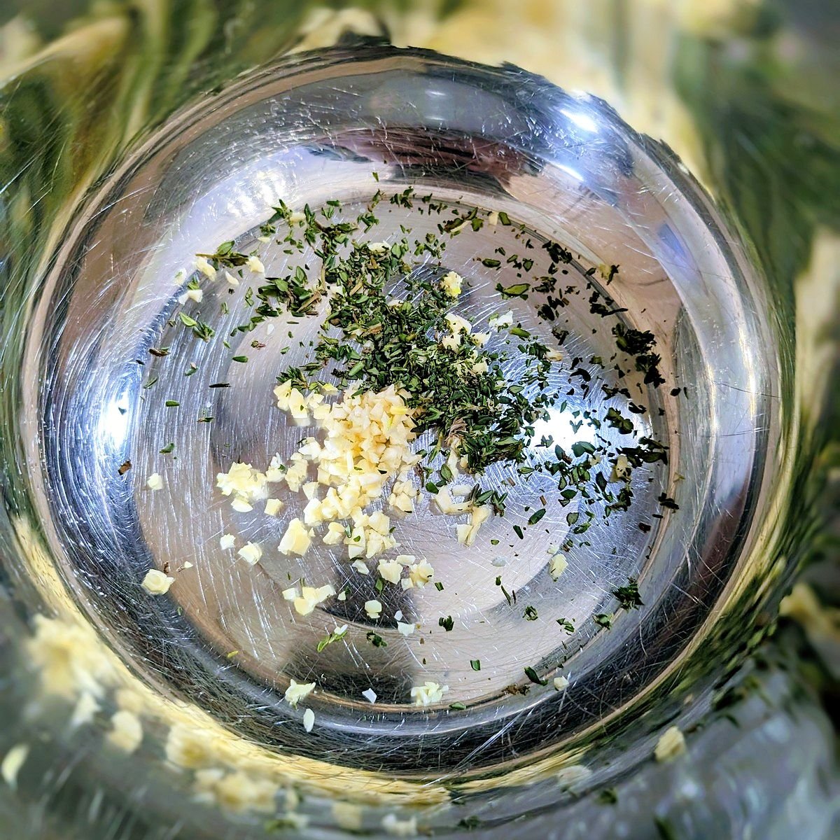 Minced garlic and fresh thyme in a mixing bowl to make balsamic chicken marinade