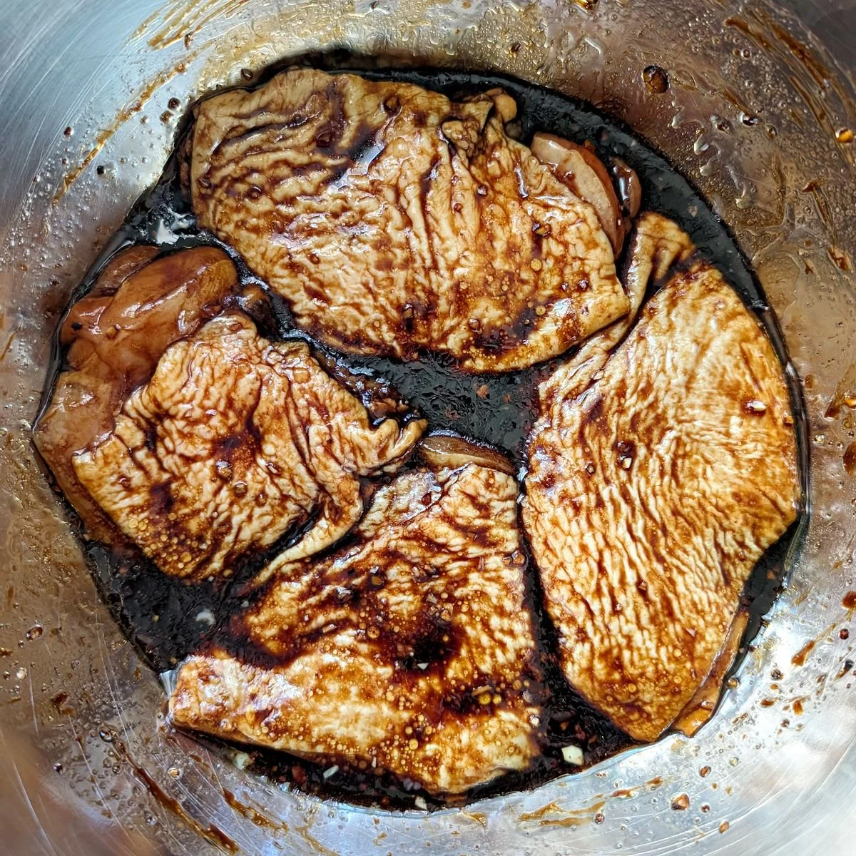 Raw balsamic marinated chicken thighs coated evenly before air frying