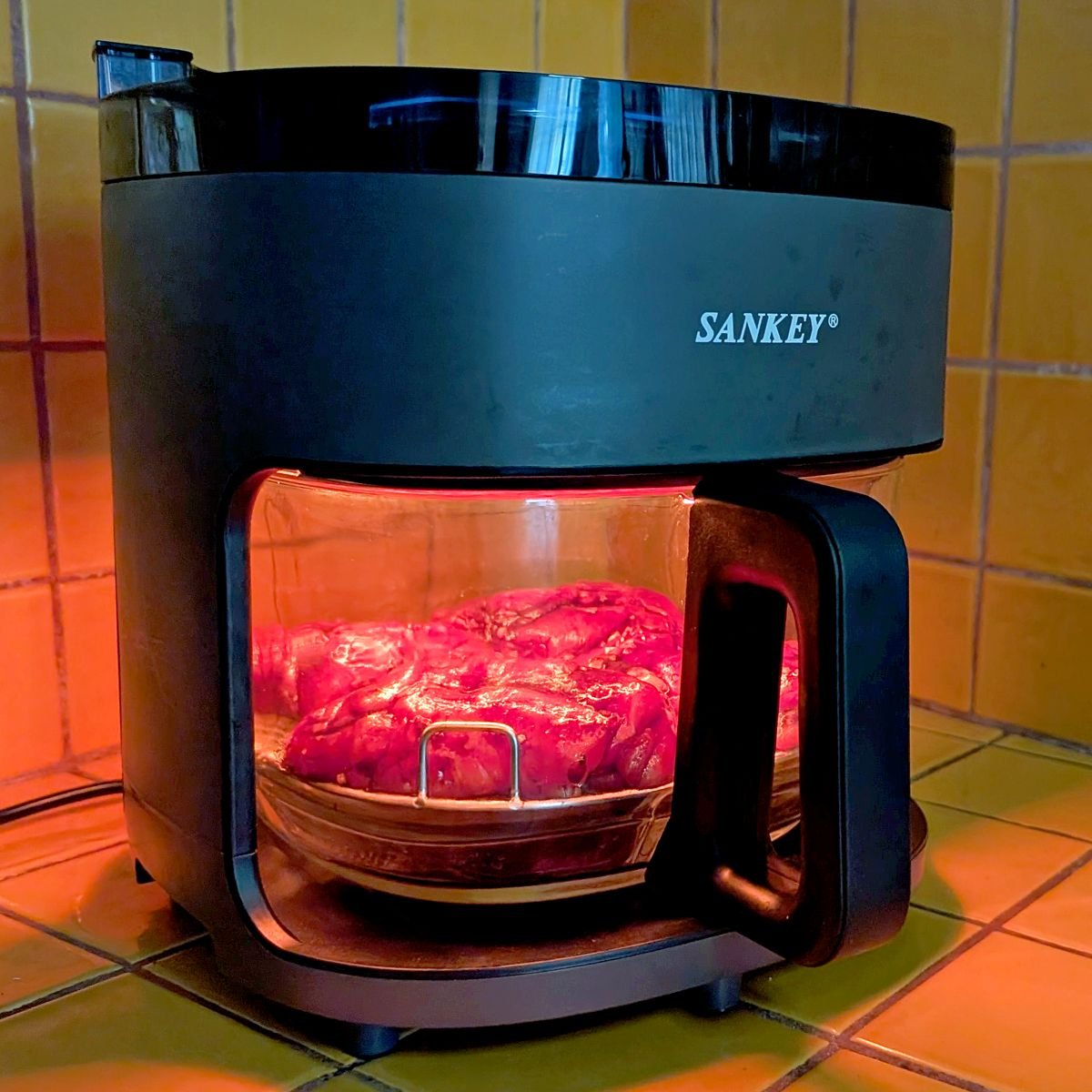 Glass bowl air fryer cooking balsamic chicken thighs inside