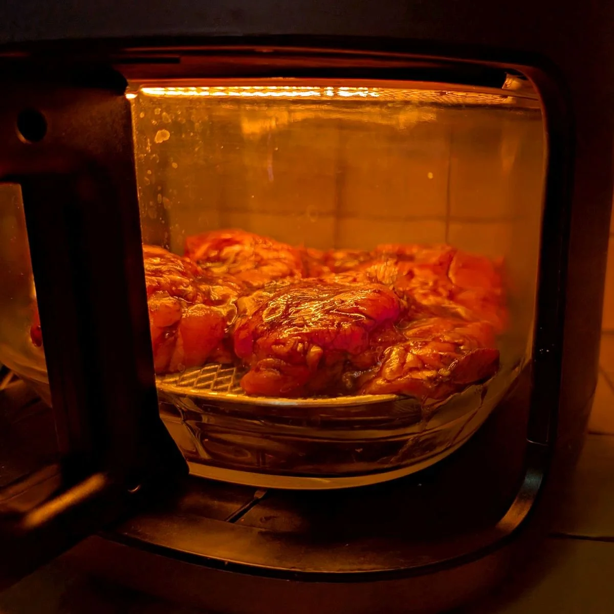 Balsamic chicken thighs cooking inside a glass bowl air fryer