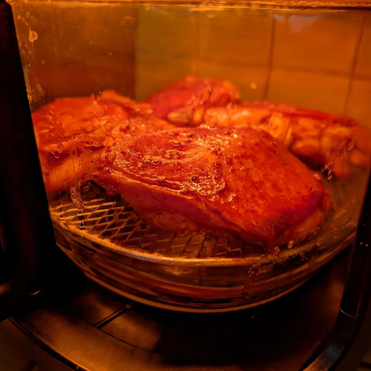 Close up of balsamic marinated chicken thighs sizzling in the air fryer basket