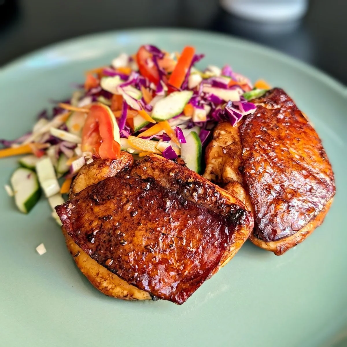 Air fryer balsamic chicken thighs served with fresh cabbage slaw on a plate