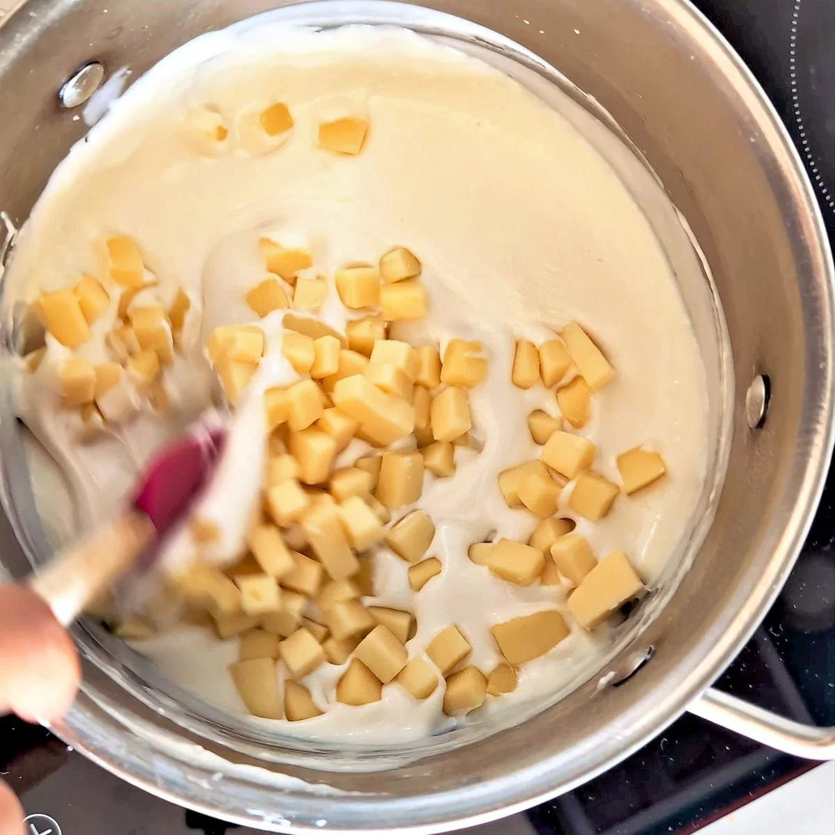 Adding cubed cheese to the hot béchamel sauce to make mornay sauce