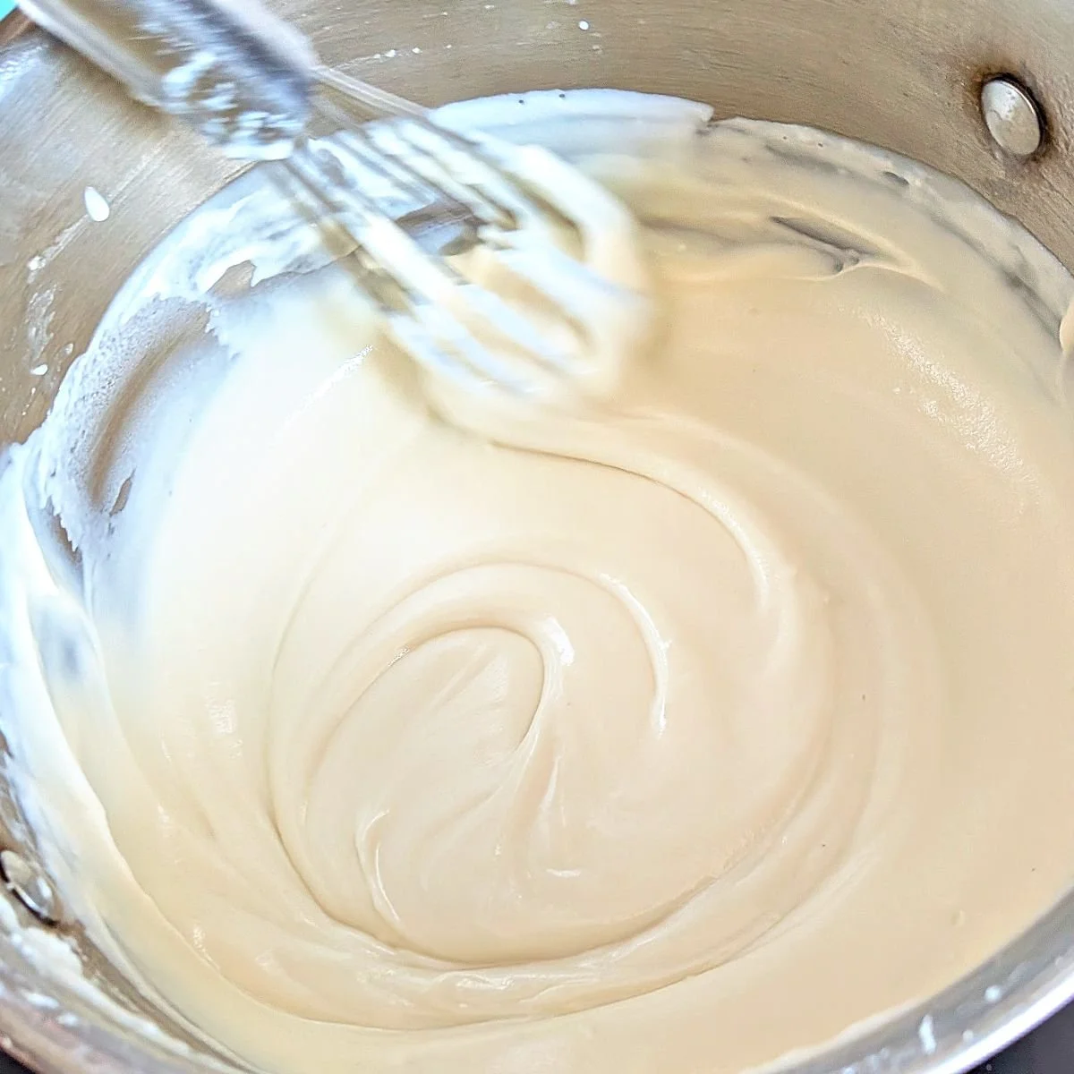 Whisking the cheese into a smooth and creamy mornay sauce until fully melted