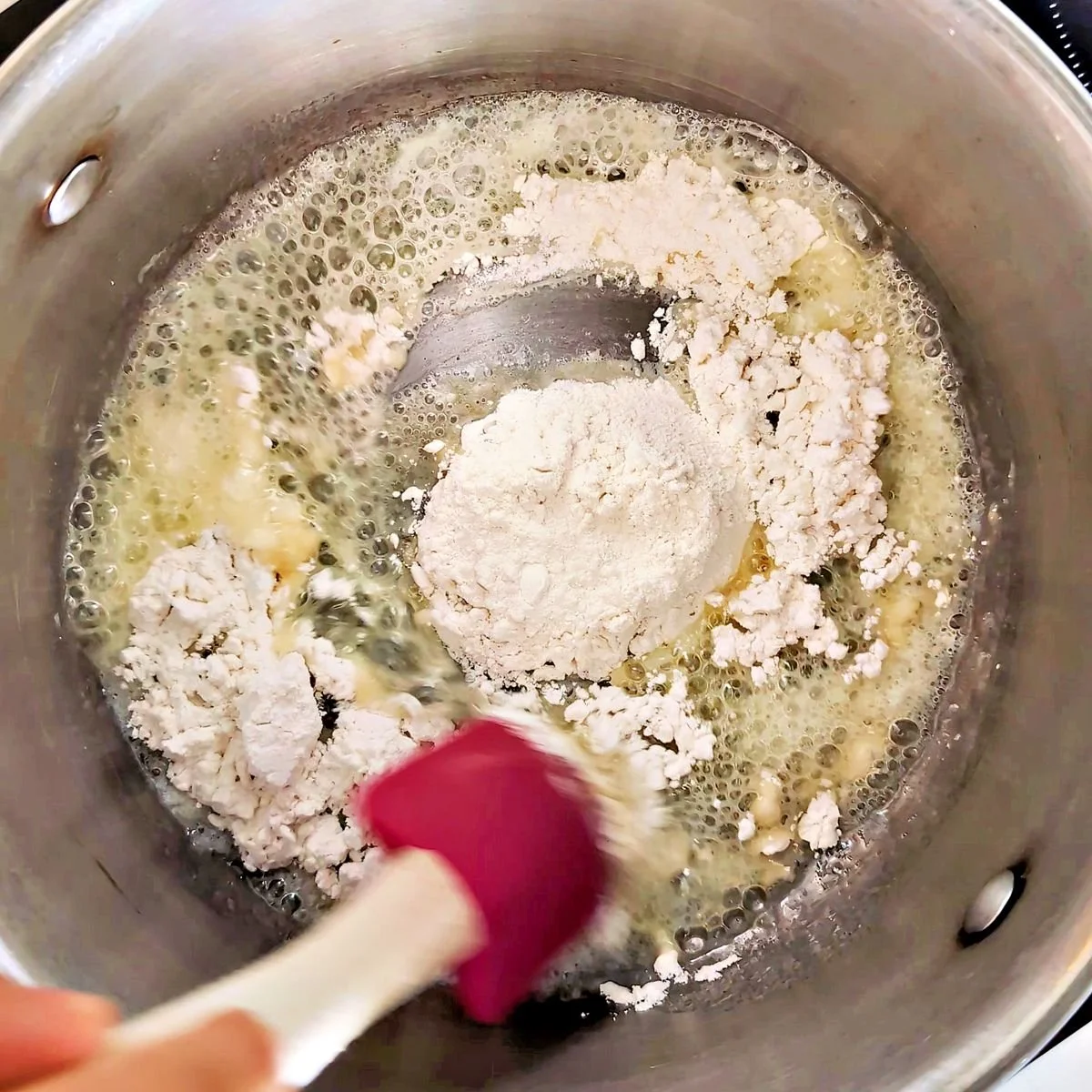 Adding flour to melted butter to make a brown roux
